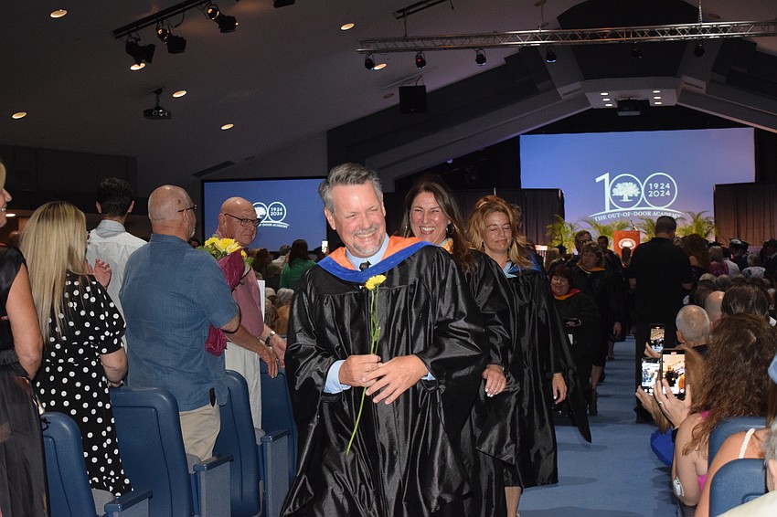 Sean Ball, the head of the upper school, laughs after receiving a flower from someone in the audience as he exits.