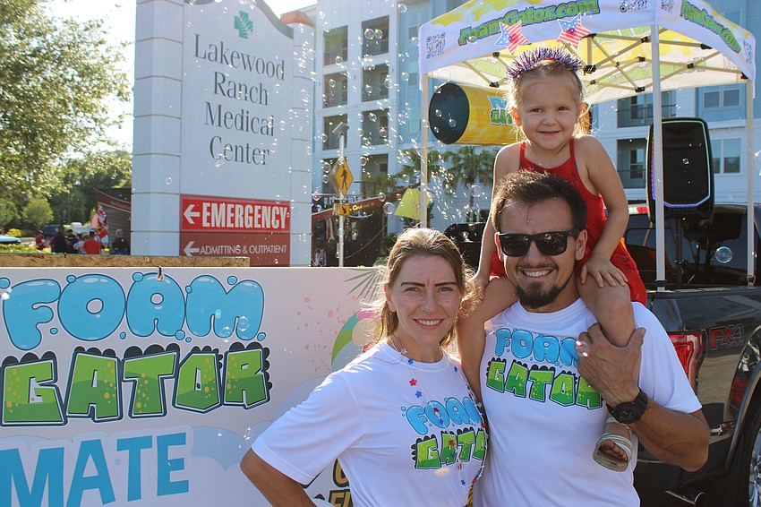 Lana and Alex Vovkulin who own the Foam Gator foam party business of Sarasota, enjoy the bubbles with their 4-year-old daughter Charlotte, before they get ready to participate in the parade.