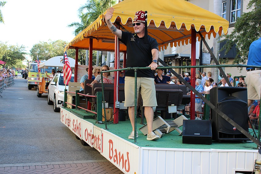 Ceremonial Master Mark Nelson waves to the crowd from the Sahib Shriners Oriental Band float.