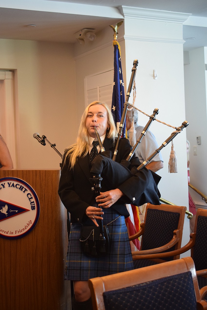 Gemma Briggs plays her bagpipes as members walk in.