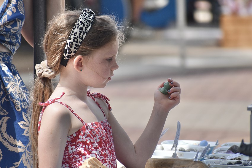 Maggie Poppoon, 6, a visitor from Texas, examines stone items at the market.