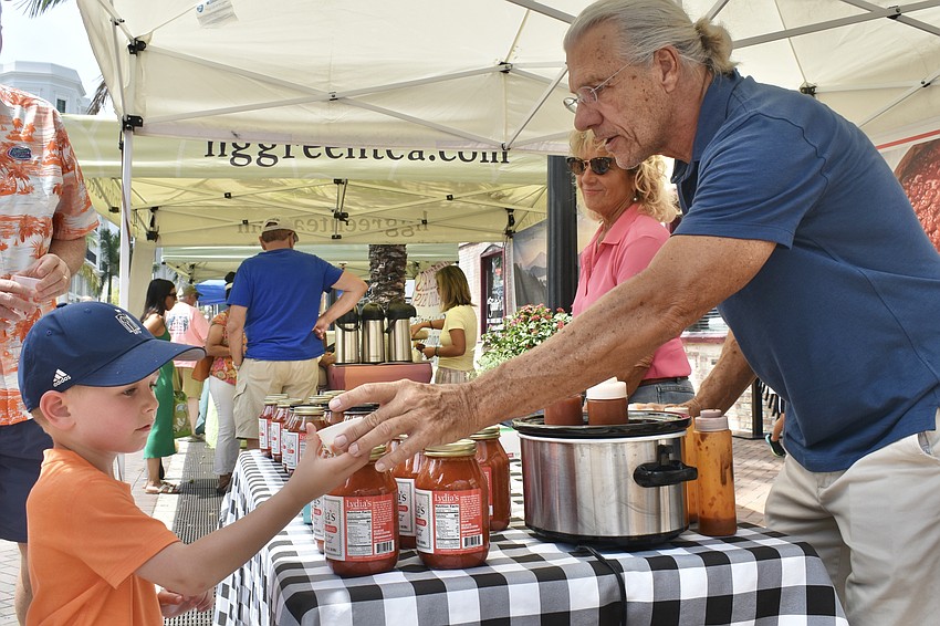 Rory Johnston, 4, samples tomato sauce by Lydia's Authentic Pasta Sauce, staffed by Lydia Roma and Jerome Agar.