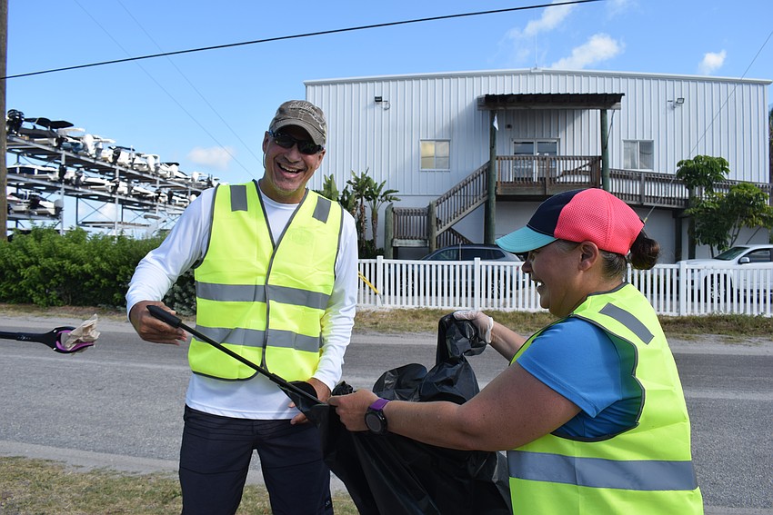 Jason Richards and Angie Long split responsibilities of picking up and holding the trash bag.