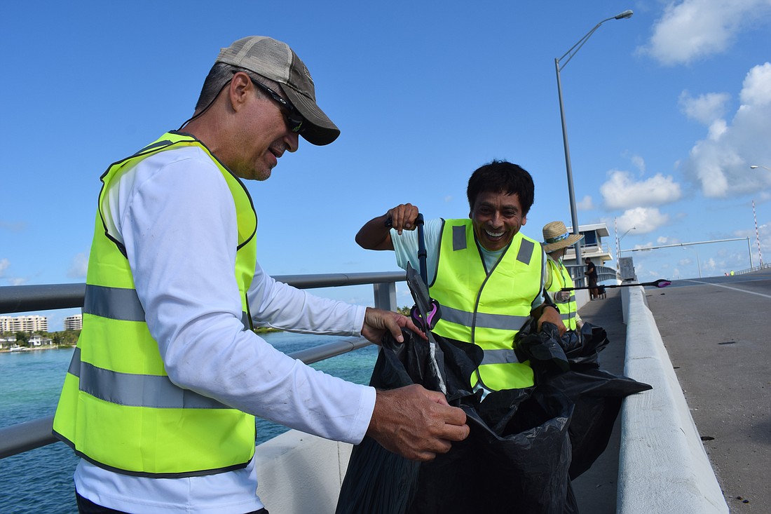 Jason Richards and Andre Hidalgo joke around while picking up car parts on Gulf of Mexico Drive.