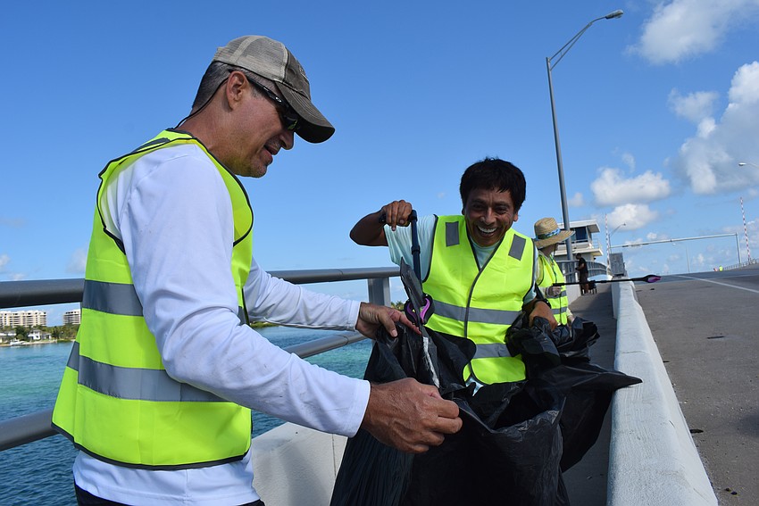Jason Richards and Andre Hidalgo joke around while picking up car parts on Gulf of Mexico Drive.