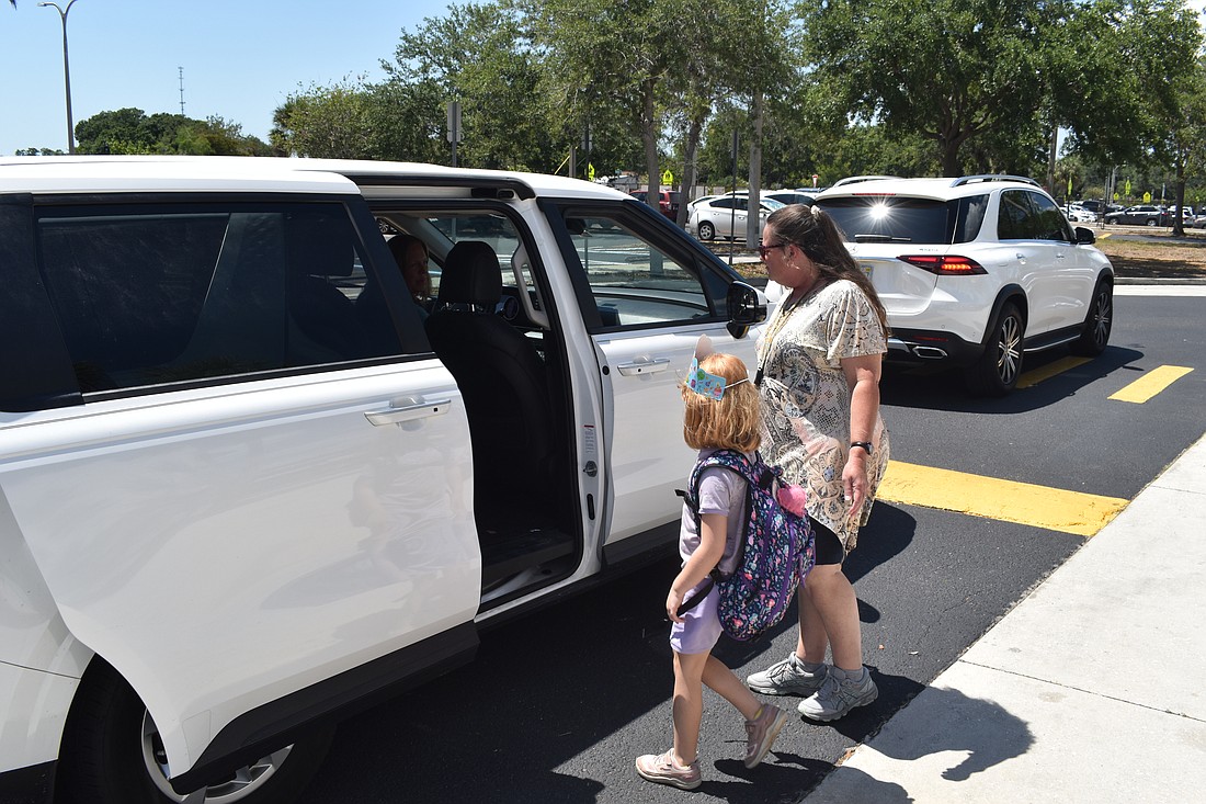 Fruitville Elementary student Summer Medvecky heads to the car with ESE Paraprofessional Cluster Aide Tammy Gauntt.