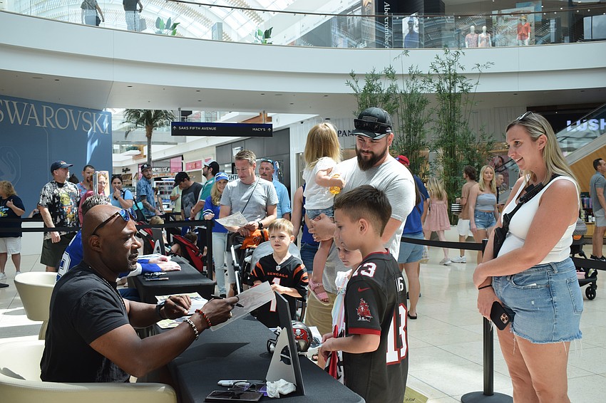 Dexter Jackson, a former Tampa Bay Buccaneers player, signs autographs for Buccaneers fans Savanna Stoner, Brian Stoner, Emma Stoner, Mason Stoner and Casaundra Stoner.