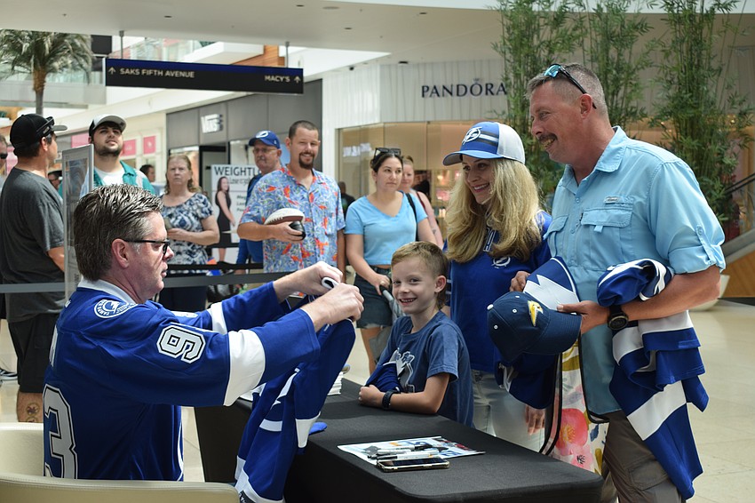 Former Tampa Bay Lightning player Daren Puppa signs gear for Sarasota 7-year-old Abraham Bouchane and his parents, Rosie Bouchane and Andre Bouchane. 