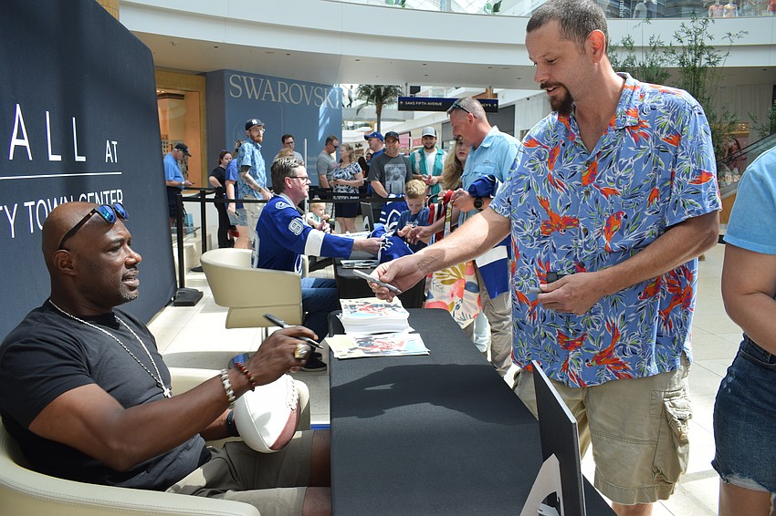 Dexter Jackson, who played for the Tampa Bay Buccaneers, adds his signature to a football filled with other players' signatures for North Port's Anthony Saponara.