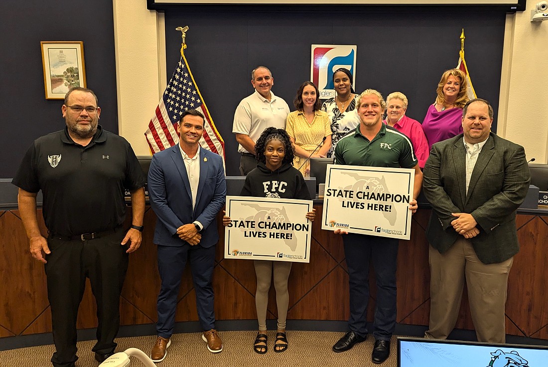 The Flagler County School Board honored Flagler Palm Coast's High School's state athletic champs on June 18. Pictured are girls wrestling champ Joslyn Johnson and boys shot put champ Colby Cronk with FPC throws coach Paul Spegele (left), the school district's Tommy Wooleyhan and FPC athletic director Scott Drabczyk. Another wrestling champ, Christina Borgmann, was out of town for a competition. Photo by Brent Woronoff