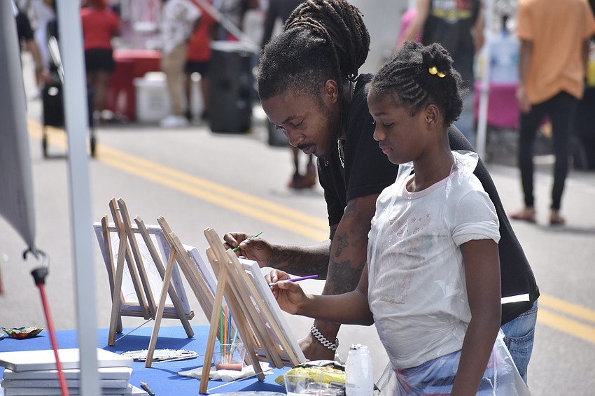 Dinero Allen and his daughter Faith Allen, 9, take part in a painting activity.