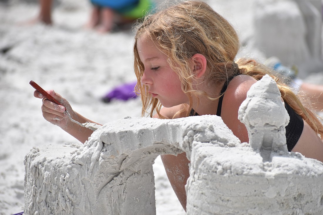 Josie Calderon, 9, removes some sand from a sculpture.