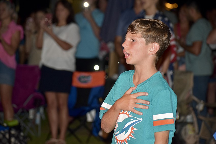 Parrish resident Parker Thielking, 9, sings along to the National Anthem before the fireworks begin.