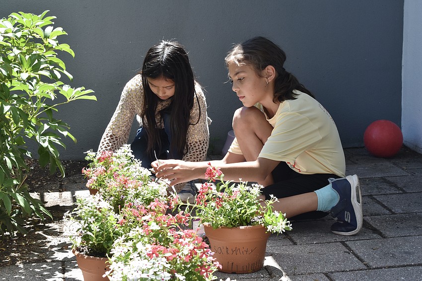 Claudia R., 9 and Anastasia V., 8 set their flower pots beside the other finished pots.