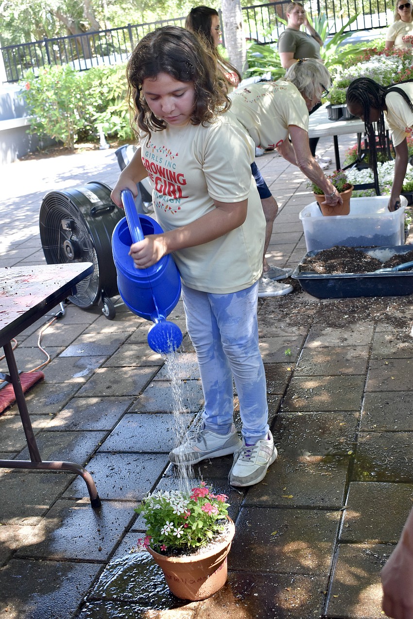 Gabriella M., 9, waters her plant.