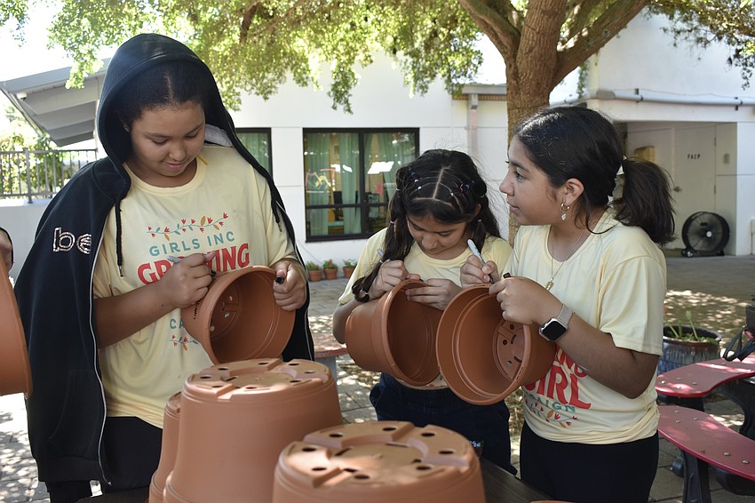 Brianni W., 12, Williannys M., 12 and Juliet Q. sign their flower pots.