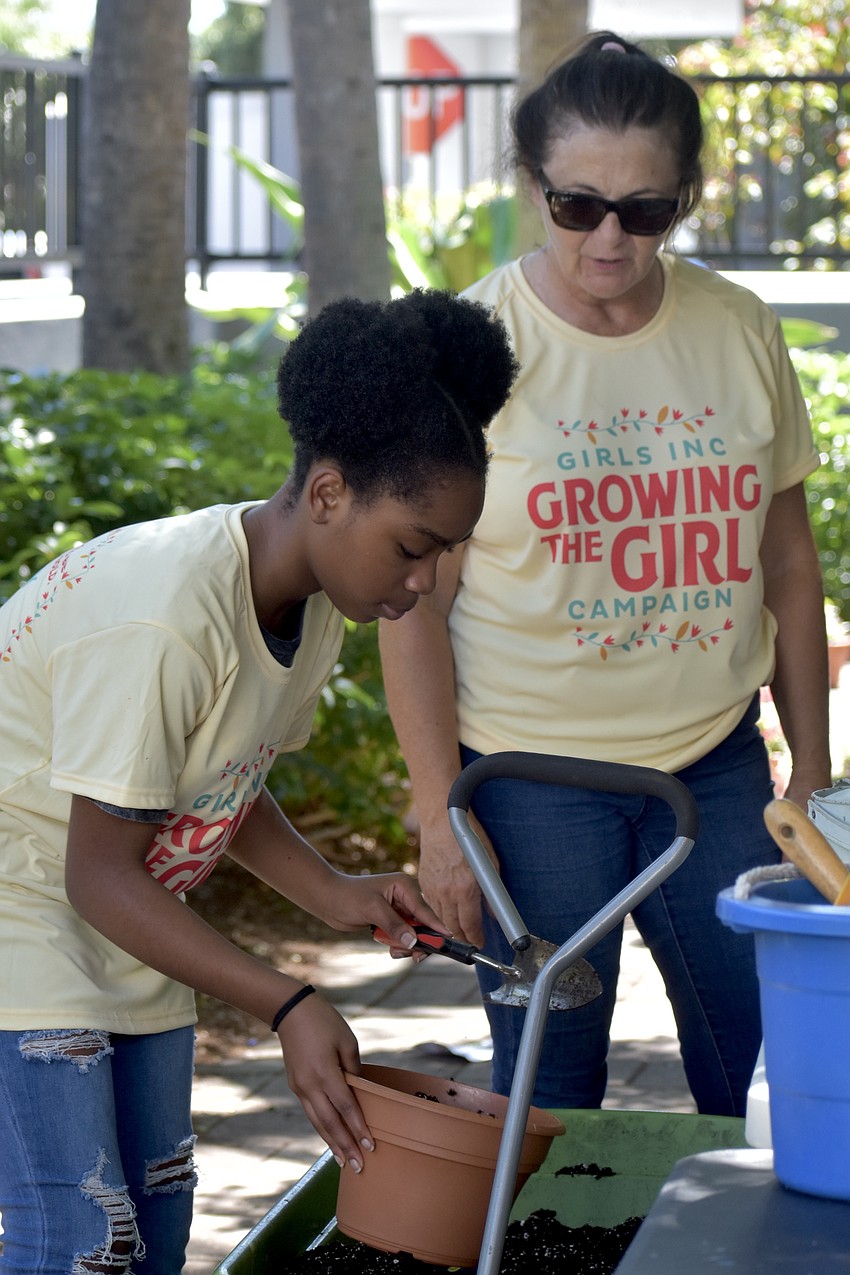 Rejii'Nae Peterson, 12, scoops the dirt, beside Terri Kelley of Sun-Fire Nurseries