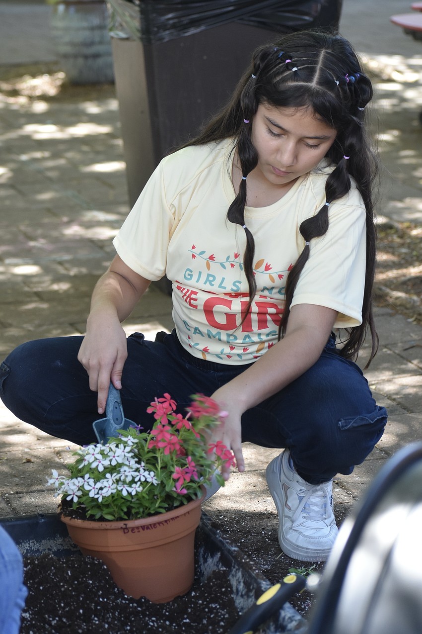 Williannys M., 12, adds soil to the flower pot.