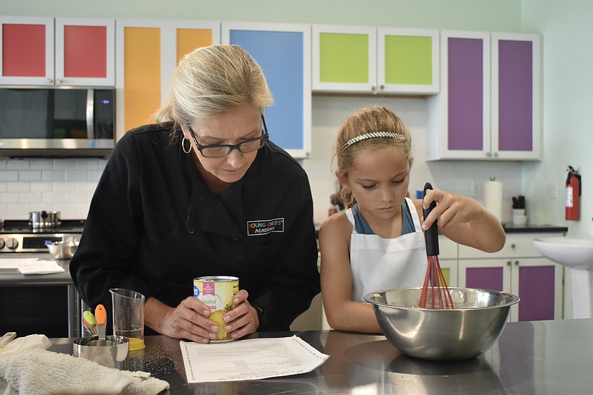 Instructor Rebecca Thomas and Indie Lewis, 7, mix ingredients.