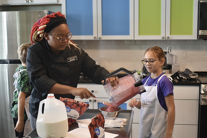 Instructor Orijah Dasher pours the red section of a red, white and blue smoothie which Ellie Rodgers, 9, is eager to enjoy.