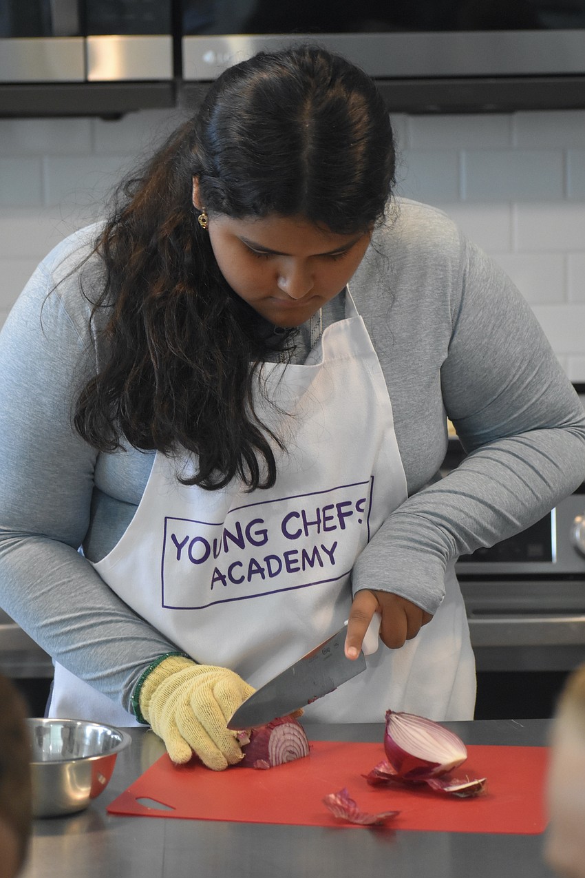 Delaney Saldivar, 12, slices an onion.