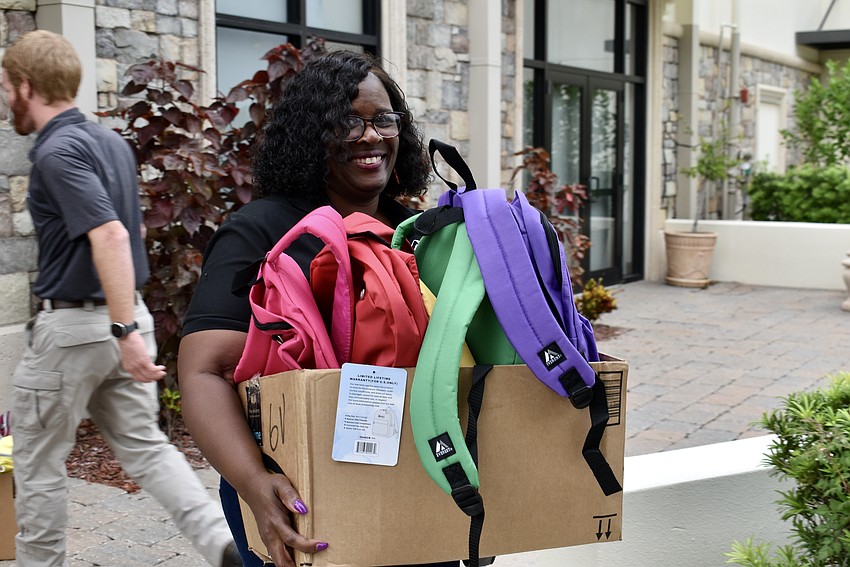 Kelli Dixon, Chief Development Officer for the Boys and Girls Clubs of Manatee County, carries a box of backpacks out to the van.