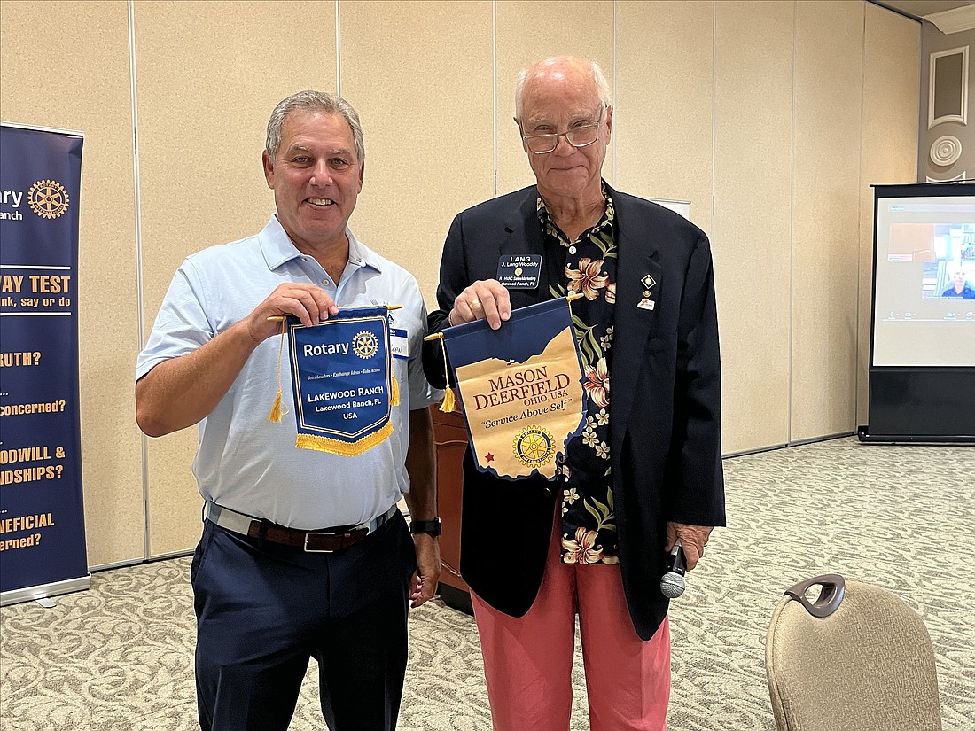 Garry Kohn, a visiting member from the Mason Deerfield Rotary Club, presents a banner to Lang Wooddy, the new Rotary Club of Lakewood Ranch president.