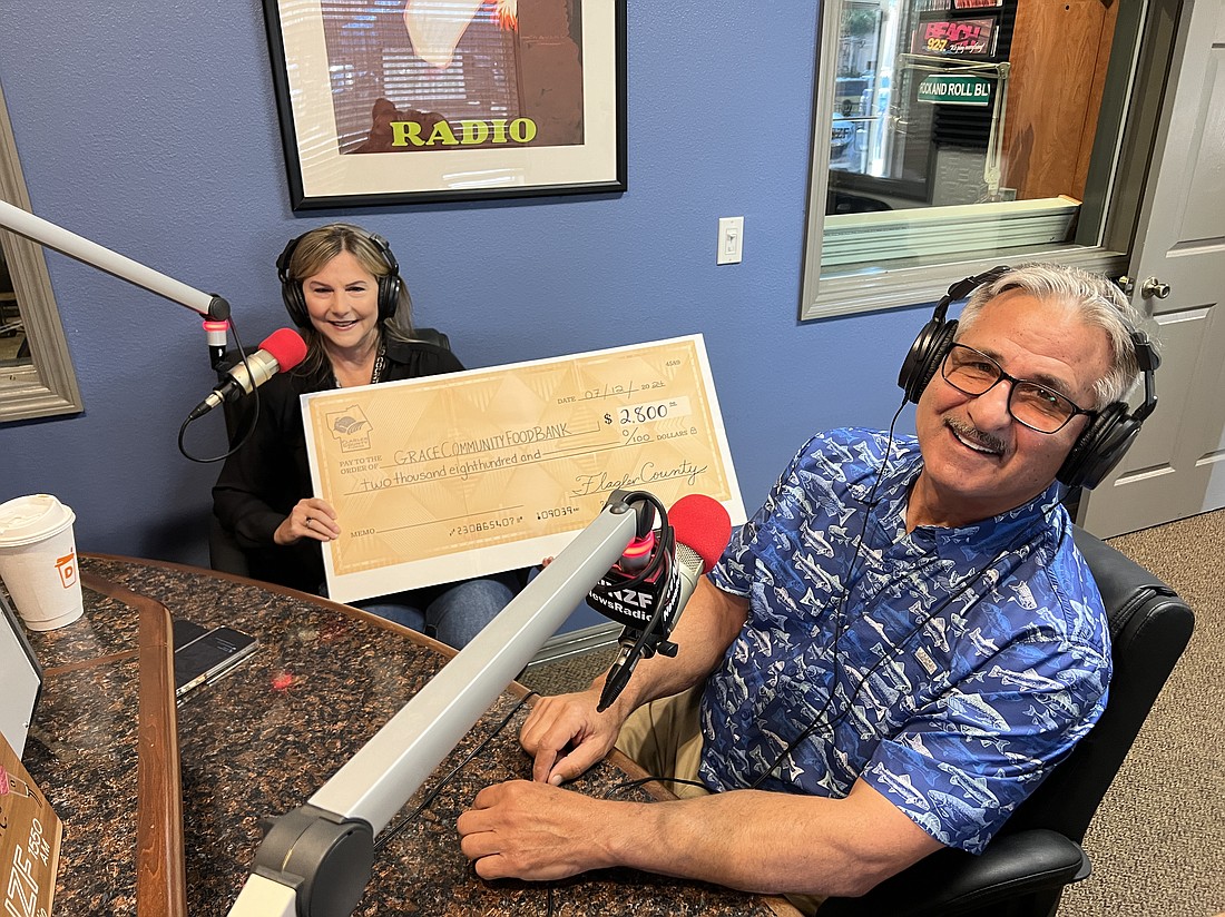 Holly Albanese presents $2,800 to Charles Silano and the Grace Community Food Pantry, on July 12, at Flagler Radio. Photo by Brian McMillan