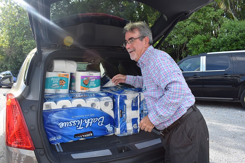 New Stillpoint Mission president Gary Scott loads his car with toilet paper donations from Longboat Island Chapel.