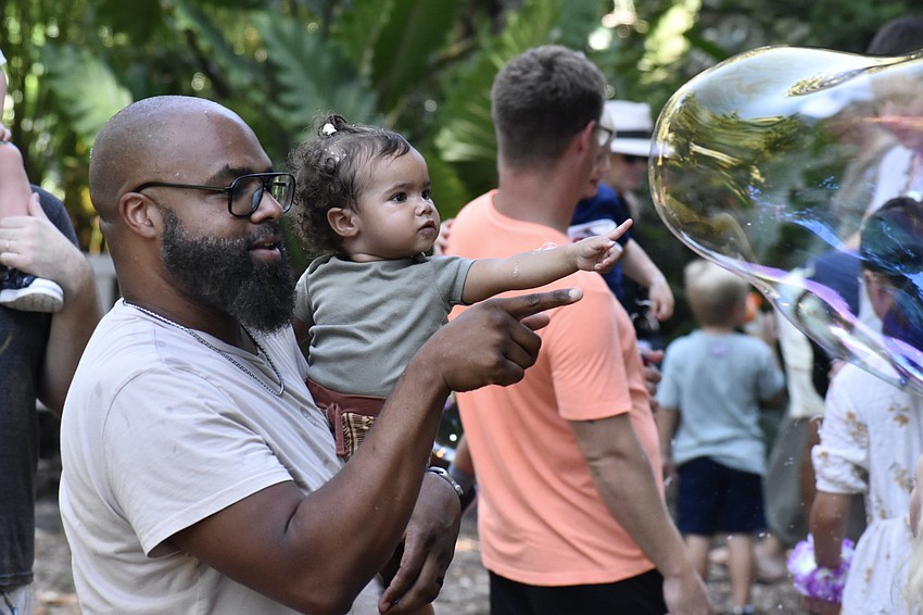 Kelvin Belser and his daughter Kassandra Belser, 1, try to pop the bubbles.