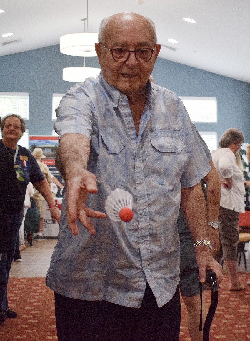 Bob Henderson tries his best to land a badminton birdie in a container.