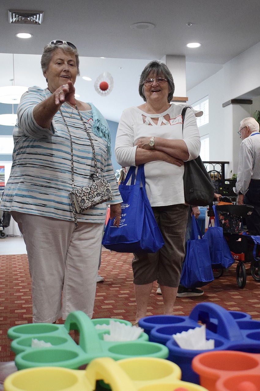 Linda Vest successfully launches 12 badminton birdies into containers as her friend Mary Appledorn watches. Vest credited years of being a University of Kentucky basketball fan for her abilities.
