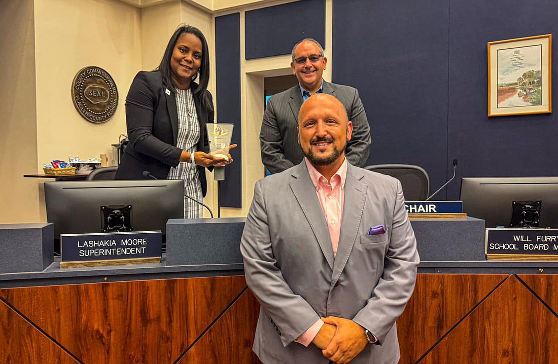 Palm Coast-Flagler Regional Chamber of Commerce President Greg Blose (center) poses with Superintendent LaShakia Moore and School Board Chair Will Furry after presenting Moore with the Chamber's Excellence in Action Award. Courtesy photo from Flagler Schools