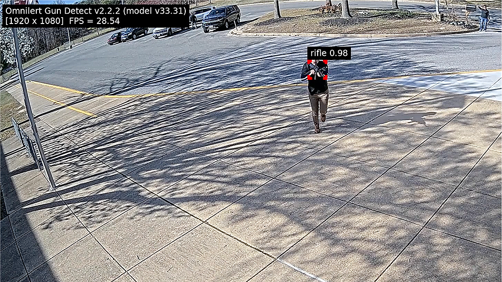 The Omnilert Gun Detect system recognizes a rifle a man is holding as he approaches a building. The software can alert school personnel and police in a matter of seconds.