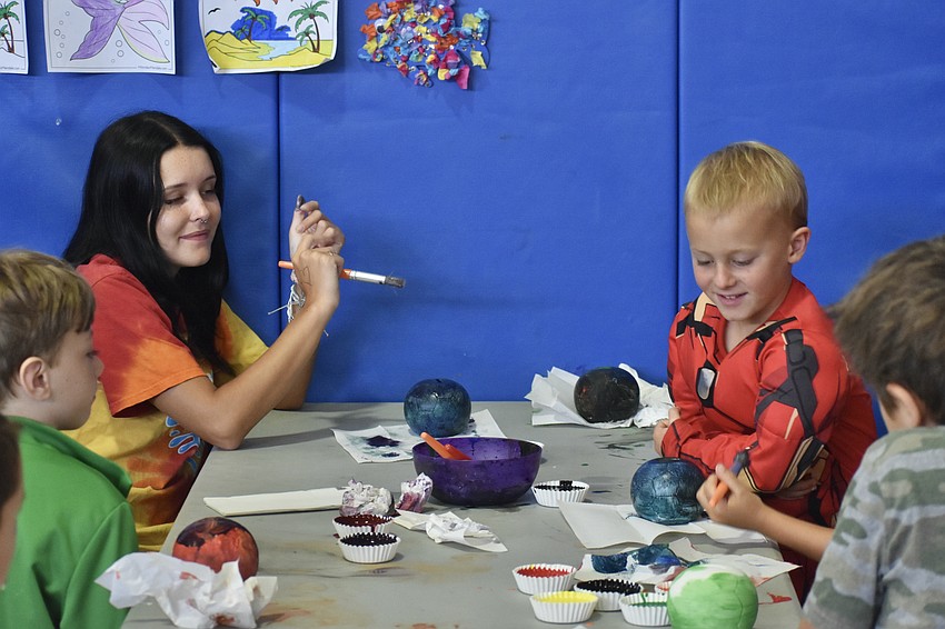 Couneslor Elizabeth Thayer, 18, and other campers including Eli Daniel, 5, work on an art project.