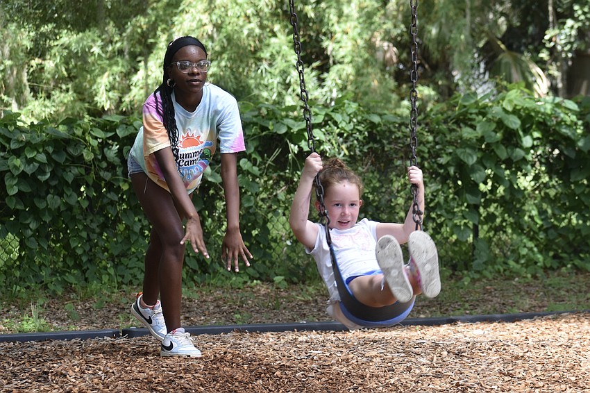 Couneslor Sa’Riyah Pitts pushes Lilly Hill, 6, in the swing on the playground.