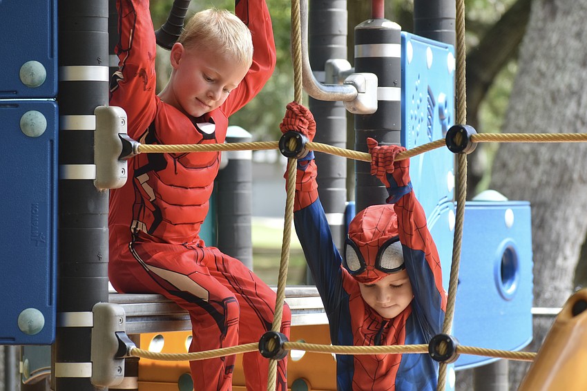 Eli Daniel, 5, dressed as Iron Man, watches Jack Kushin, 7, practice his climbing skills as Spider-Man.