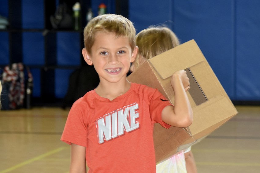 Harvey Hines, 7, helps set up boxes for a game that will involve knocking them over.