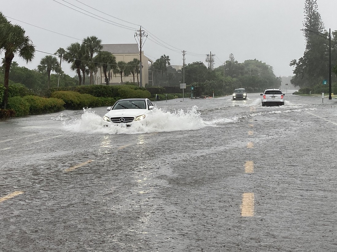 A car drives through floodwaters on Longboat Key on Sunday.