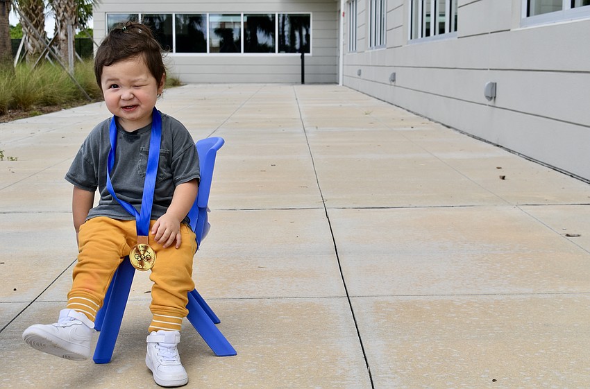 Greenbrook resident and almost 2-year-old, Roman Malinoski, takes a seat with his medal.