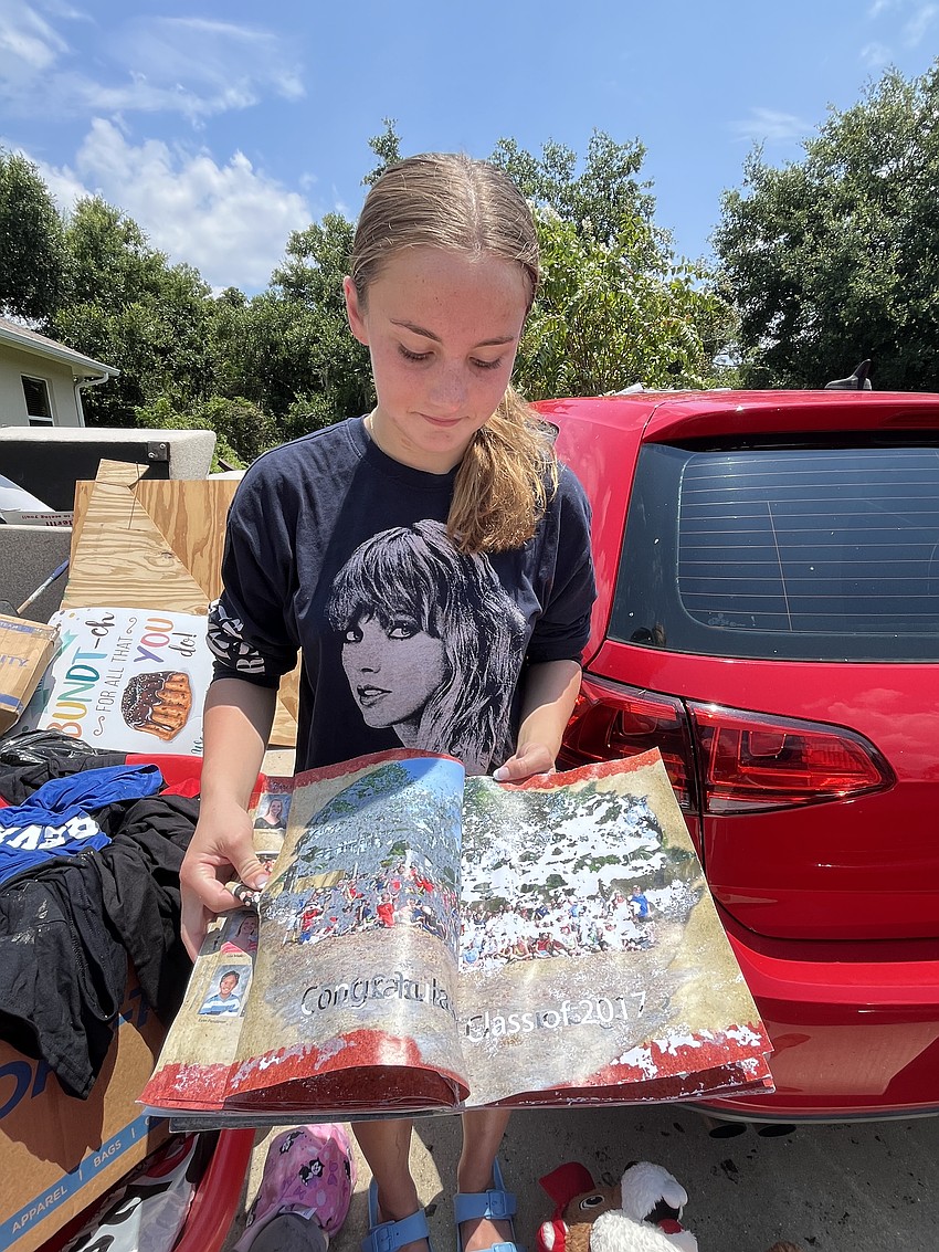 Summerfield Bluffs 13-year-old Leah Abrams looks over her destroyed yearbooks as her family works to clean up their home after it was flooded. 
