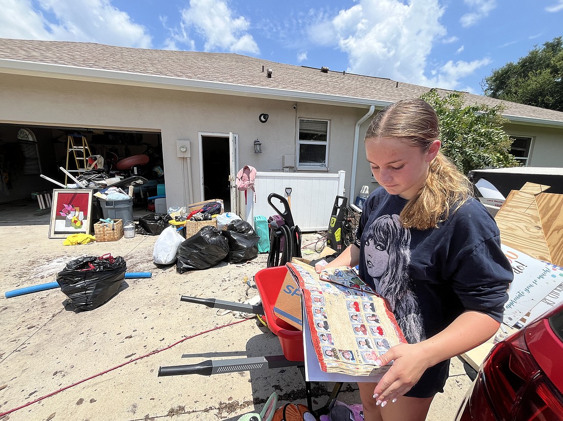 Summerfield Bluffs 13-year-old Leah Abrams looks over her destroyed yearbooks as her family works to clean up their home after it was flooded. "All of my yearbooks are ruined," she says.