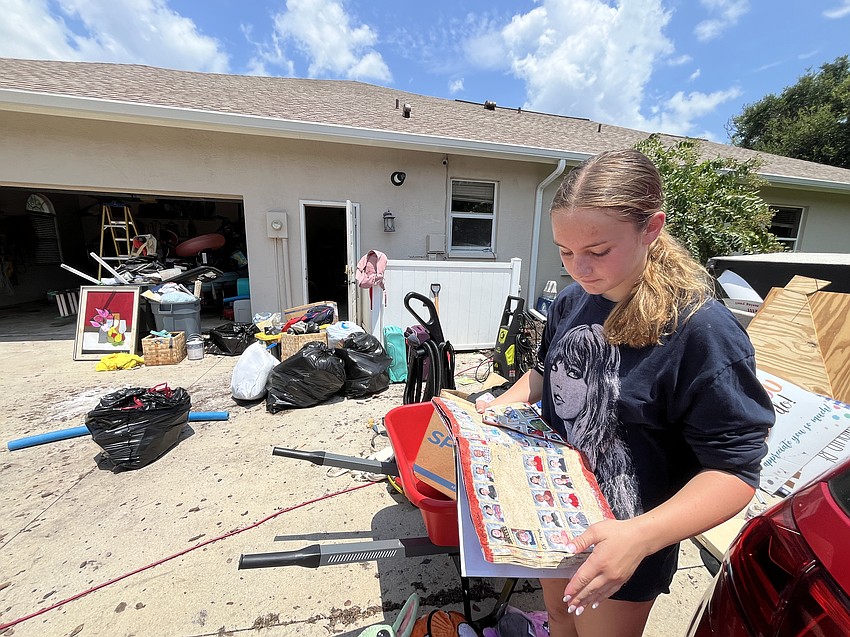Summerfield Bluffs 13-year-old Leah Abrams looks over her destroyed yearbooks as her family works to clean up their home after it was flooded. 