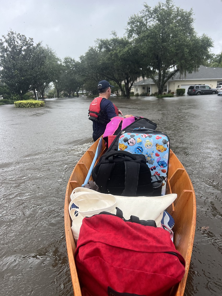Summerfield Bluffs' Jody Abrams uses a canoe he had in his garage to safely get supplies for his family out of their flooded home and to dry land.