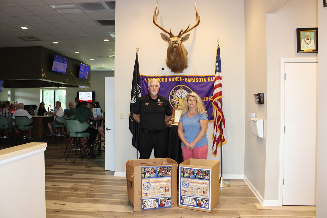 Lakewood Ranch Elks Exalted Ruler Kevin Burke and EFELT Executive Director Andrea Hitcho stand in front of bins at the Elks Club used to collect food donations.