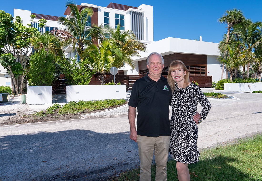 Mark and Diane Russell, who co-own Russell & Russell Construction, stand in front of 89 Beach, a luxury condominium building on Siesta Key.