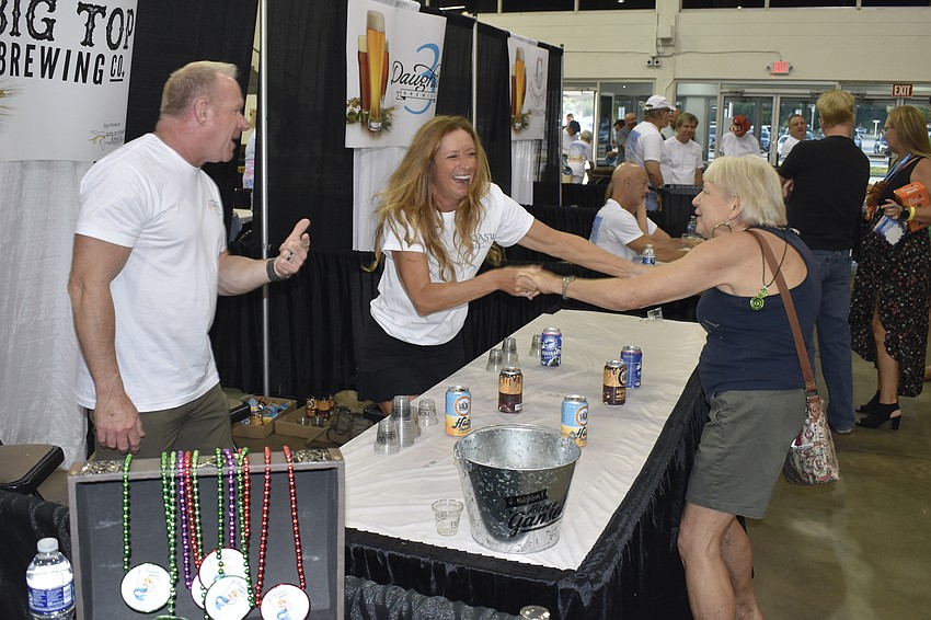 Joe Keogh watches as April Shereda dances with event attendee Trisha Alberda over the table.