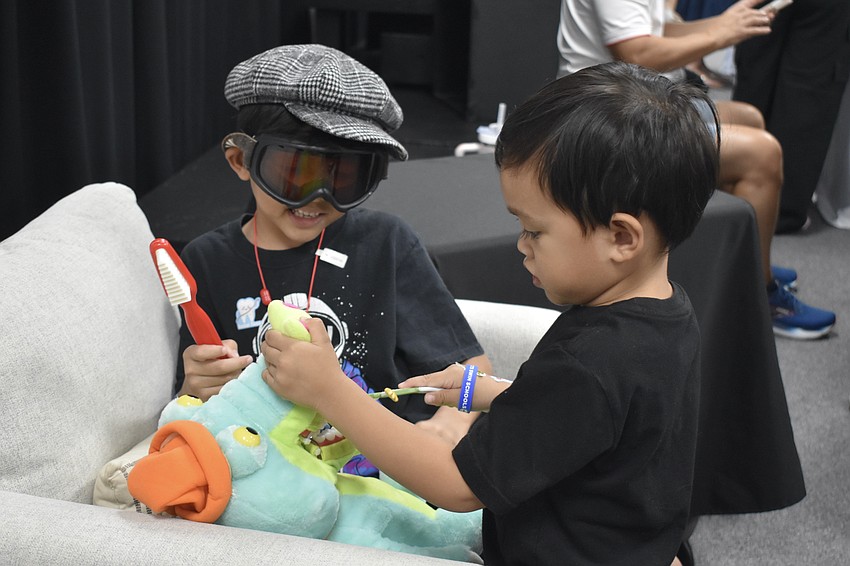 Brandon Byrd, 4, and his brother Brady Byrd, 3, brush the teeth of a crocodile at the stand of Give Me a Smile, a new pediatric dental office on Fruitville Road.