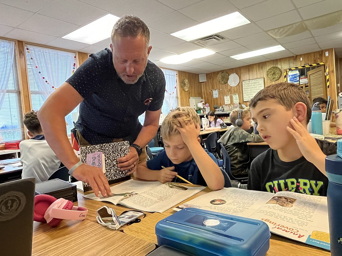 Todd Richardson, the principal of B.D. Gullett Elementary School, helps third graders Oliver Bates and Dylan Berg with a reading assignment.