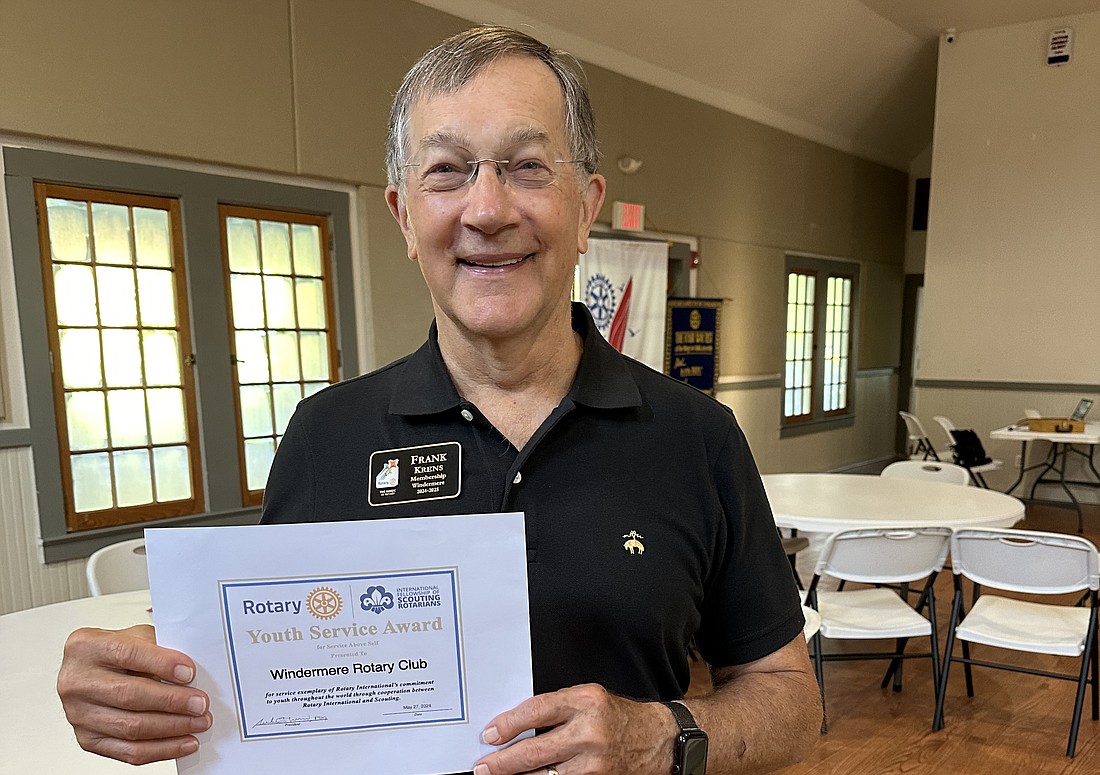 Windermere Rotary Club member Frank Krens holds up the newly earned IFSR Youth Service Award.